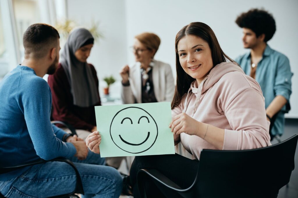 a woman holding up a drawing of a happy face